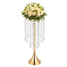 a gold vase filled with white flowers and crystal beads on top of a metal stand