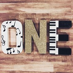 the word music spelled with musical notes and piano keys on a wooden floor in front of a sign that says one