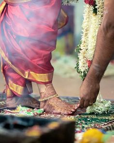 two people standing next to each other with their feet covered in flowers and garlands