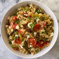 a bowl filled with rice and vegetables on top of a marble countertop next to a fork