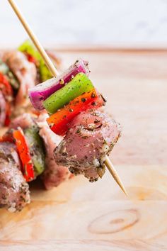 several skewers of meat and vegetables on a wooden board with toothpicks