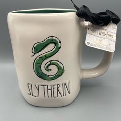 a harry potter mug with the slytherin logo on it and a black bow