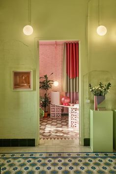 an open door leading into a room with green walls and pink curtains on the windowsill