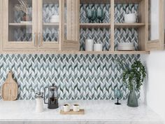 a kitchen with wooden cabinets and white marble counter tops in front of a green patterned backsplash