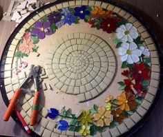 a table topped with lots of different colored paper flowers and tools on top of it