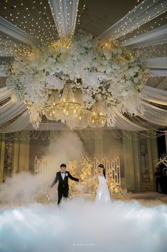 a bride and groom standing in front of a chandelier