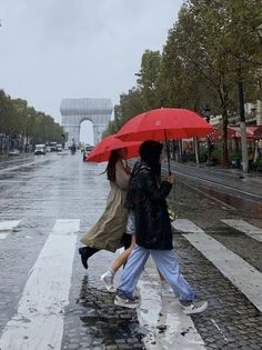 two people walking in the rain with umbrellas over their heads and one person holding an umbrella