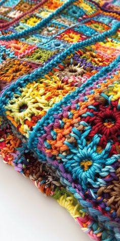 a multicolored crocheted blanket is laying on the floor with white background