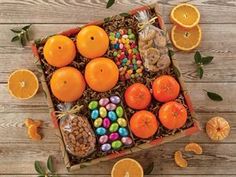 an orange box filled with lots of candies and other fruit on top of a wooden table