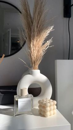 a white vase sitting on top of a table next to a bottle and some candles