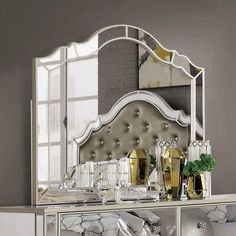 an ornate mirrored dresser with gold vases and mirrors on the top, in front of a brick wall