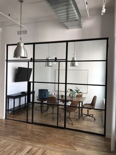 an office with glass partitions and chairs in the center, looking into the dining room