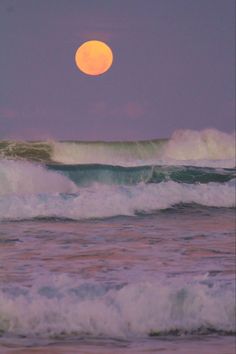 a full moon is seen over the ocean waves