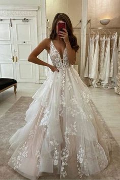 a woman taking a selfie while wearing a wedding dress with white flowers on it