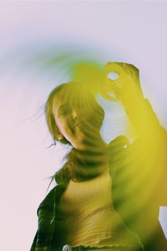 a woman is holding her cell phone up in the air with sunlight streaming through her hair