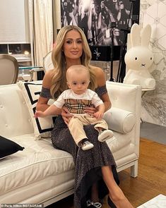 a woman sitting on top of a white couch holding a baby