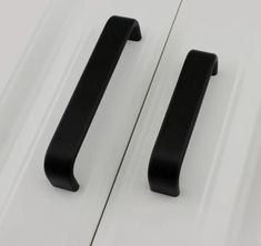 two black handles are on the side of a white car, and one has a door handle