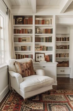 a white chair sitting on top of a rug in front of a bookshelf