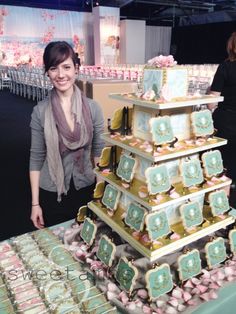 a woman standing next to a large stack of cakes