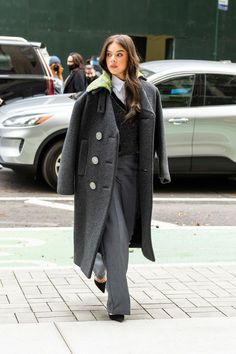 a woman is walking down the street wearing a coat