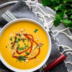 a white bowl filled with carrot soup and garnished with parsley