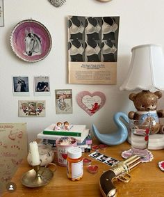 a wooden table topped with lots of assorted items next to a wall covered in pictures