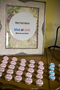 a table topped with lots of pink and blue cupcakes