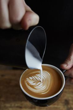 a person pouring milk into a cup of coffee