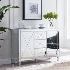 a white sideboard with a black chair and potted plant in the corner next to it