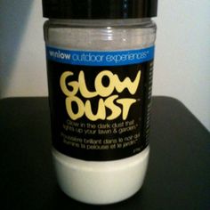 a jar of glow dust sitting on top of a black table next to a white wall