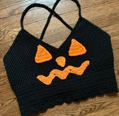 a crocheted bag with an orange and black face on it sitting on top of a wooden floor