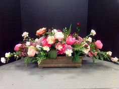 an arrangement of pink and white flowers in a wooden container