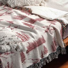 a white and red blanket sitting on top of a wooden bed next to two pillows