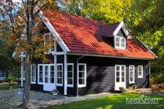 a black house with red roof and white windows