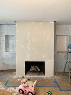 an unfinished room with a fire place and toys on the floor