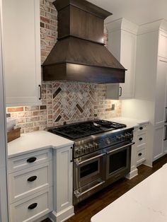 a stove top oven sitting inside of a kitchen next to white cupboards and drawers