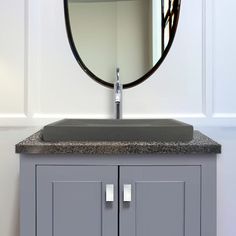 a bathroom sink sitting under a mirror next to a wall mounted faucet and cabinet