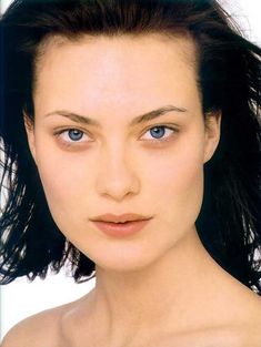 a woman with blue eyes and long black hair is posing for a photo in front of a white background