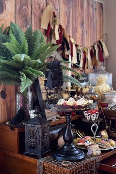 a table filled with lots of food next to a plant and wooden wall behind it