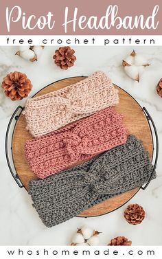 three crocheted headbands sitting on top of a wooden plate next to pine cones