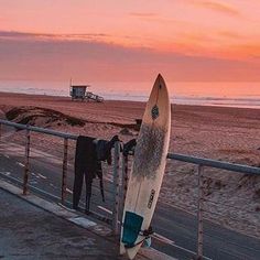 a surfboard leaning against a fence on the beach