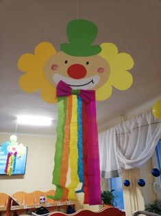 there is a large paper clown decoration hanging from the ceiling in front of a table