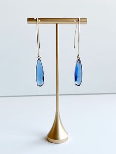 Blue Pendant Earrings ⟡ all items are designed and handcrafted in our studio ⟡ Long blue glass and gold teardrop earrings. These stunning teardrop earrings feature a beautiful blue glass stone set in a gold plated over brass setting, adding a pop of color and luxury to any outfit. The long ear wire adds a simple yet dramatic look that can be dressed up or down for any occasion. OVERVIEW-3" in length-glass crystals-gold plated over stainless steel ear wiresLooking for more threader earrings? Clic Gold Teardrop Earrings, Blue Pendant, Long Dangle Earrings, Dramatic Look, Filigree Design, Threader Earrings, Stunning Earrings, Beautiful Gift Boxes, Pendant Earrings