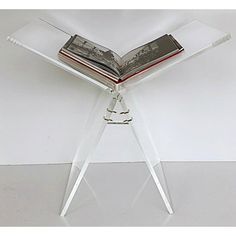 an open book sitting on top of a glass table with a magazine holder underneath it