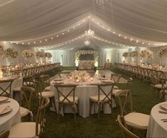 the inside of a tent with tables and chairs set up for a formal dinner party