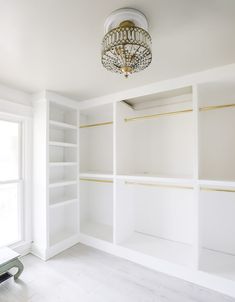 an empty room with white shelving and a chandelier