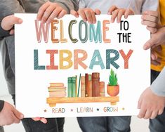 three children holding up a sign that says welcome to the library read learn grow with books and plants