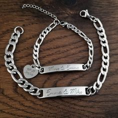 two personalized bracelets with engraved names on them sitting on a wooden table top