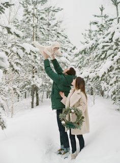 two people are standing in the snow with their arms around each other and one person is holding something up