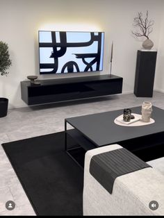 a modern living room with black and white furniture in front of a flat screen tv